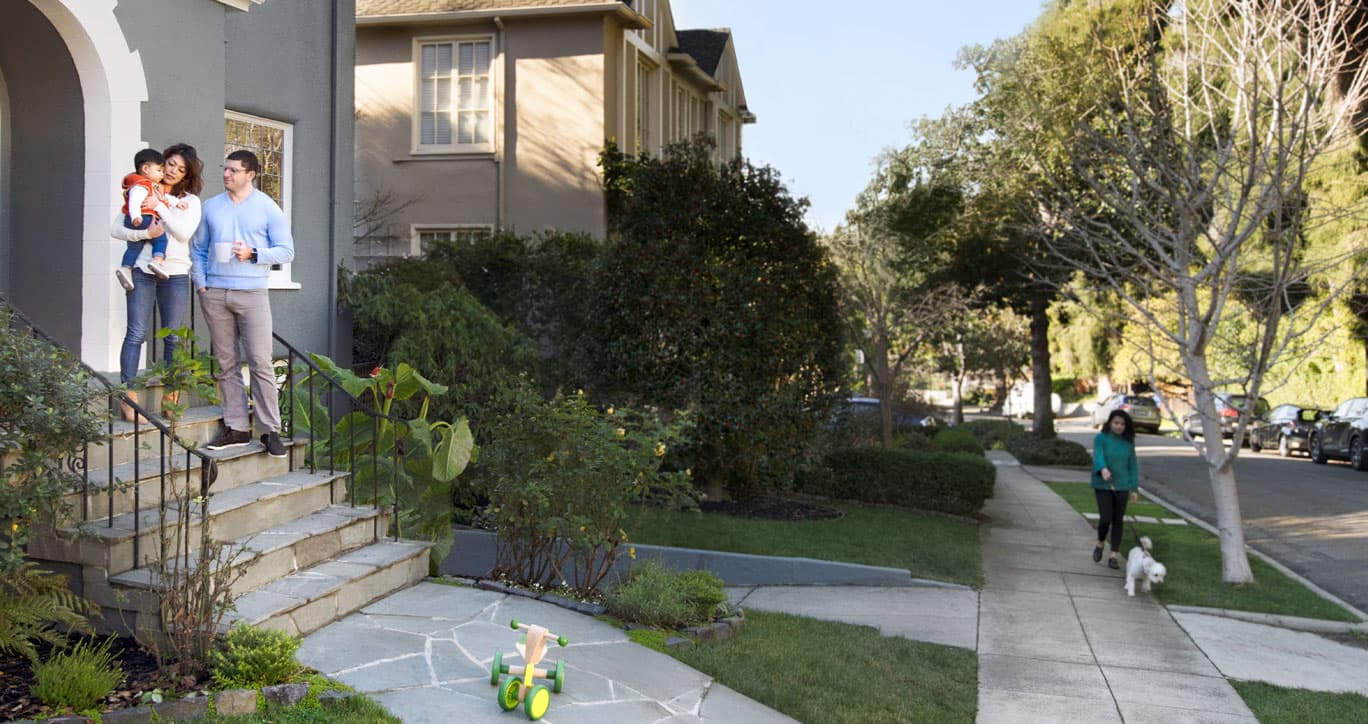 Neighbors outside their homes on a tree lined street